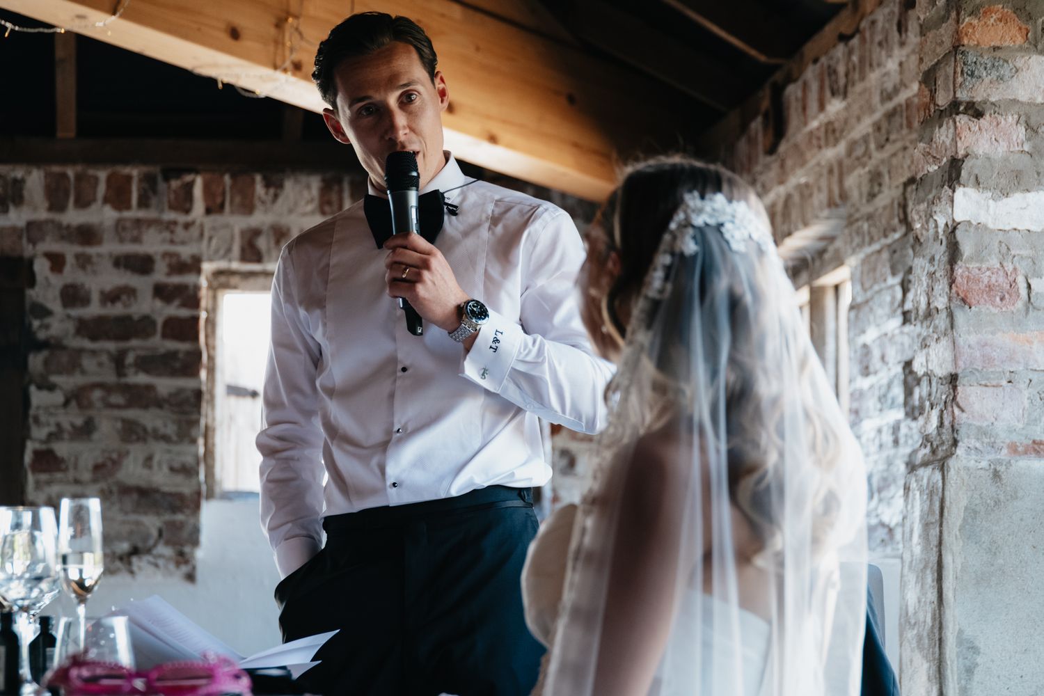 Wedding reception venue with exposed brick walls and wooden ceiling beams.