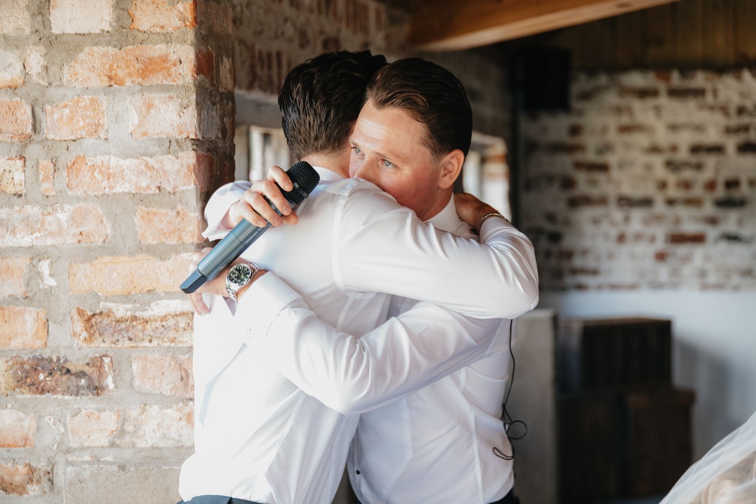 Candid celebratory moments at a rustic wedding reception with exposed brick walls.