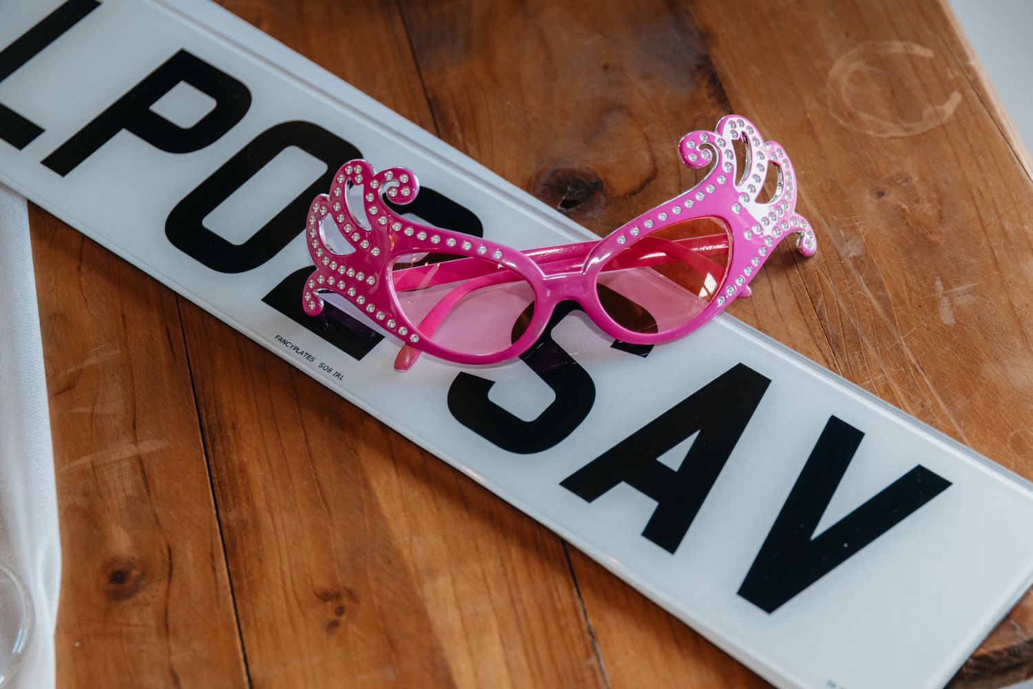 A pink ribbon lies on a wooden surface next to black text signage.