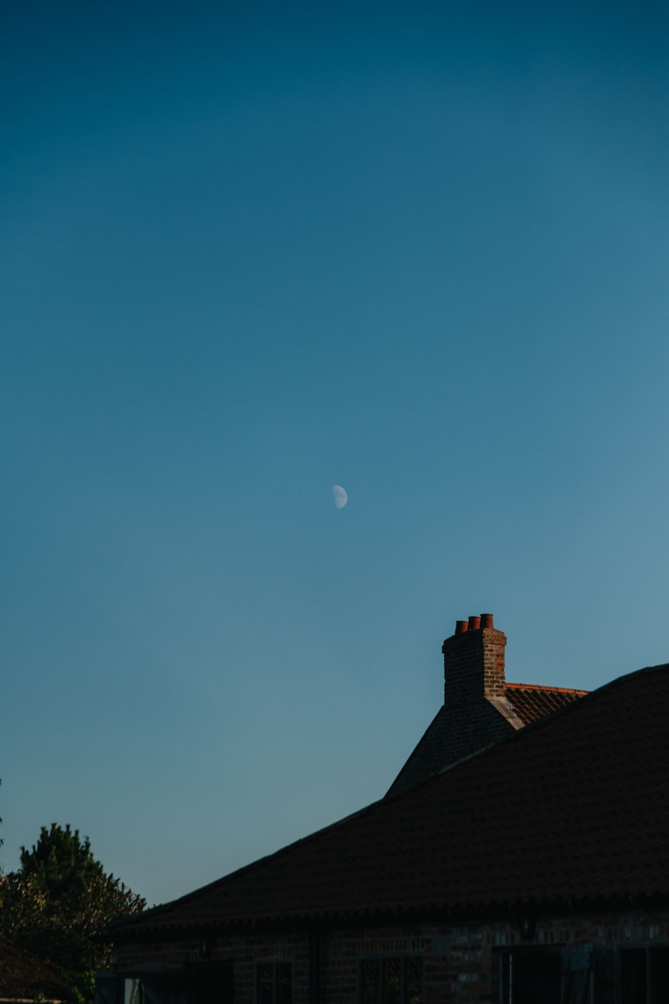 Silhouettes of rooftops against a deep blue dusk sky.