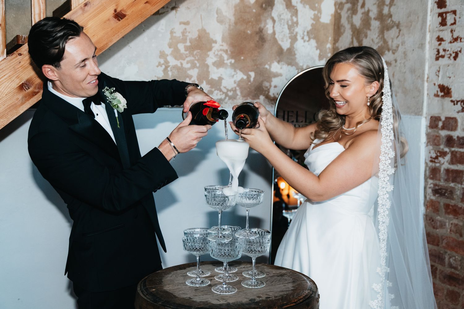 Newlyweds and guests toasting with champagne glasses in rustic brick venue.