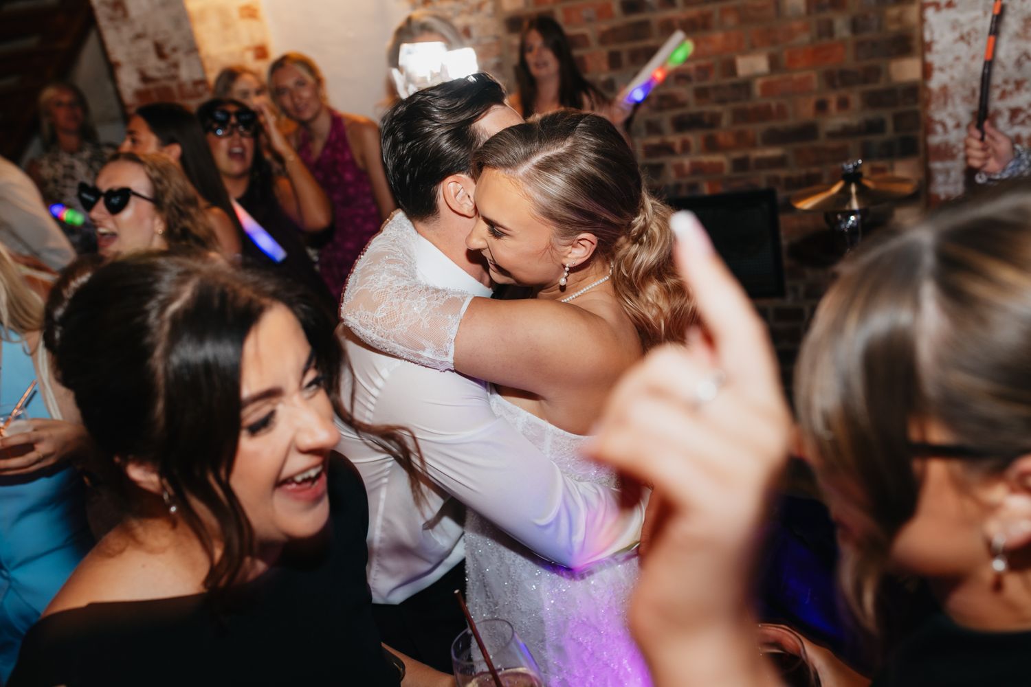 Wedding reception dance floor filled with energetic celebrating guests under colorful lights.