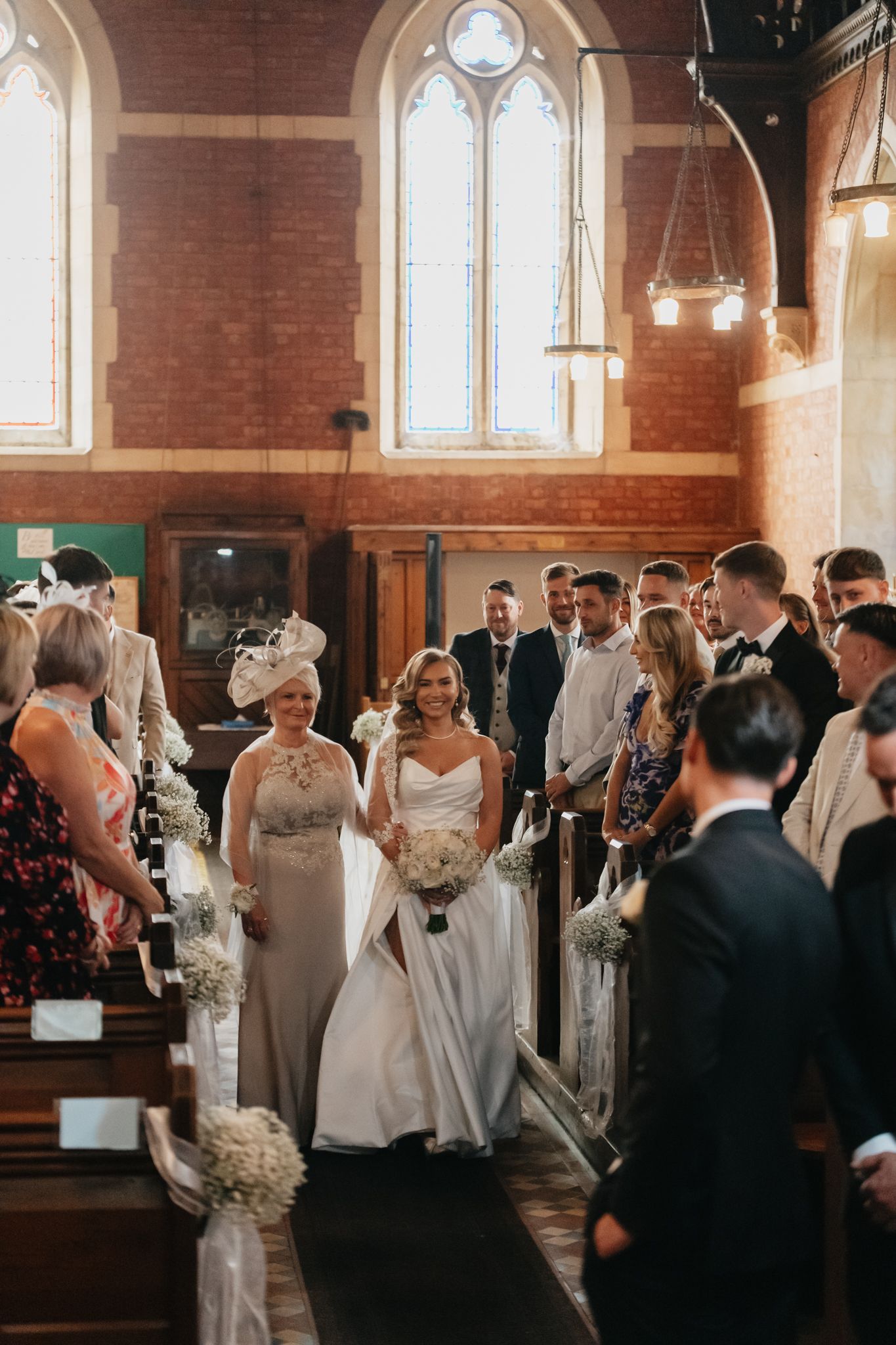 Wedding ceremony taking place in a traditional brick church with stained glass windows.