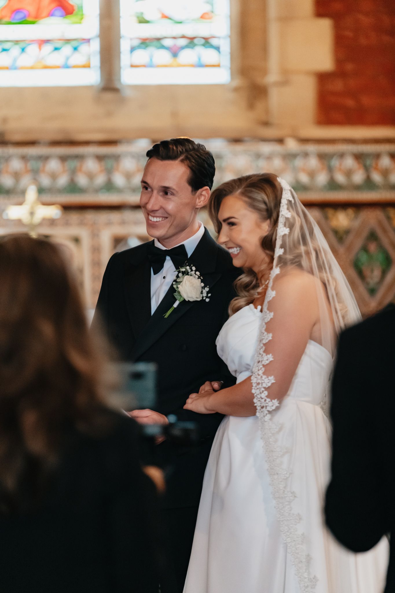 Traditional church wedding ceremony with stained glass windows and elegant decor.