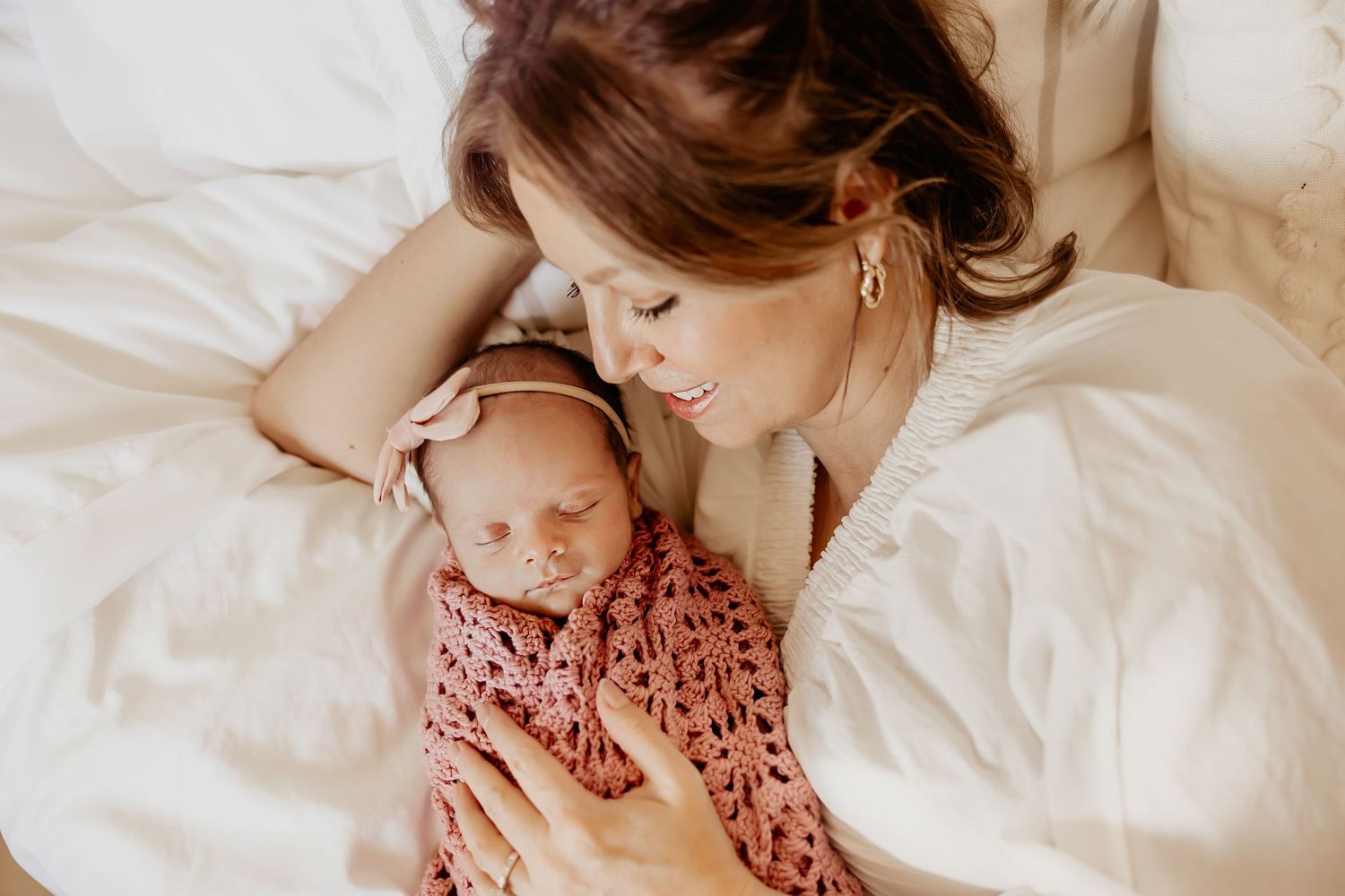 An Oahu newborn photographer captures a mother looking down at her newborn baby girl while she sleeps.