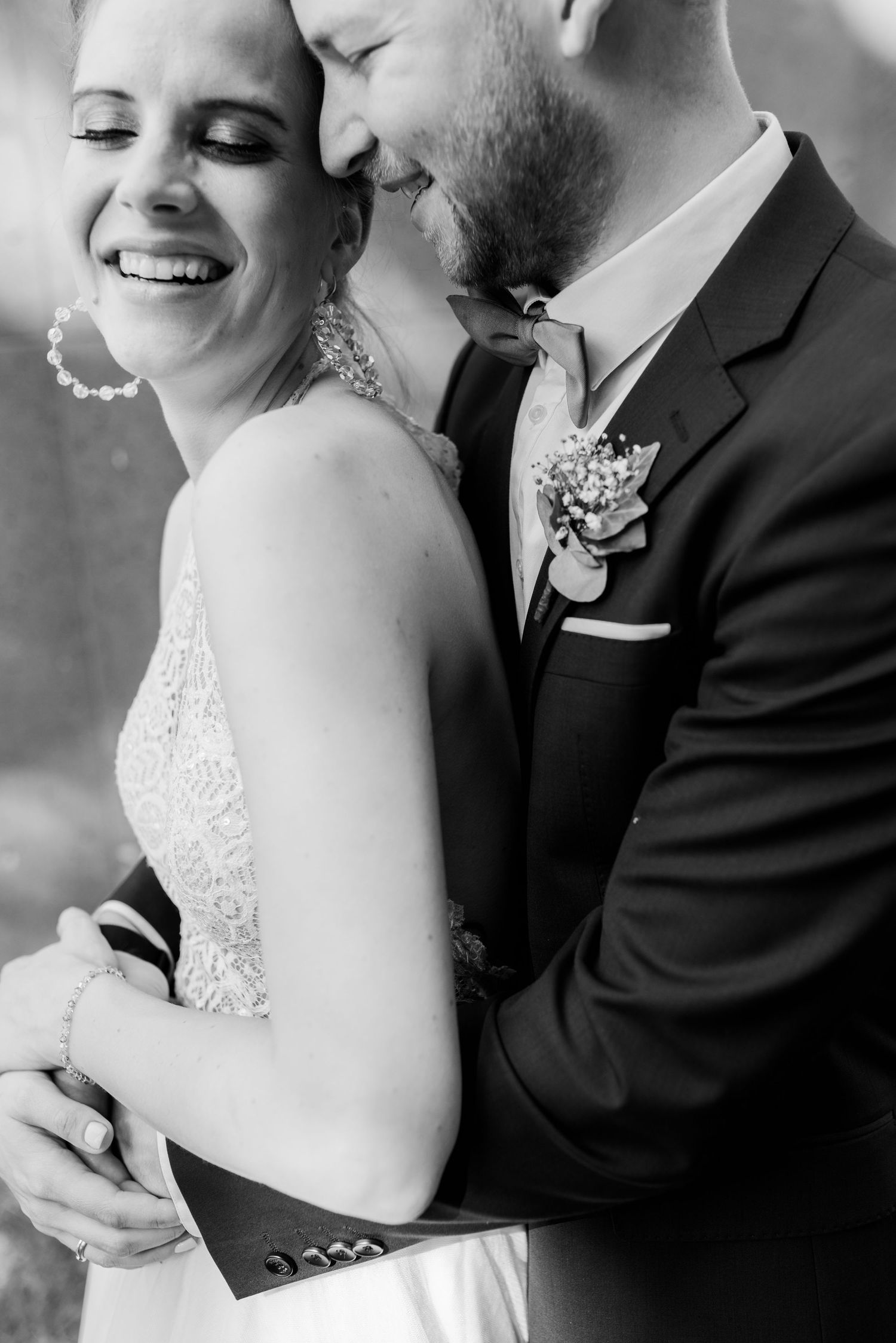 A tender black and white wedding portrait showing an intimate moment between newlyweds in formal attire.