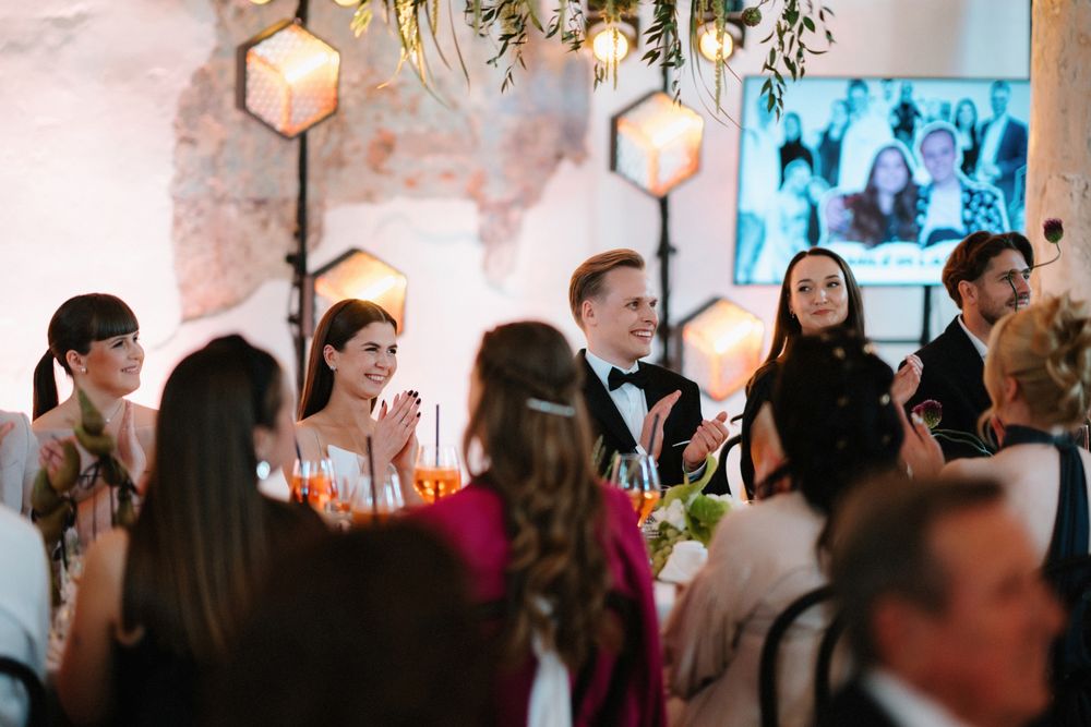 Warm-lit reception venue with hanging lanterns and greenery decorations.