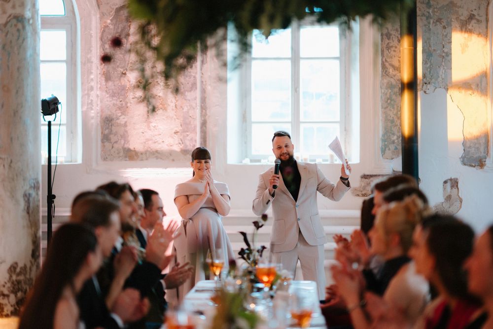 Elegant event space with natural light streaming through windows and decorative foliage.