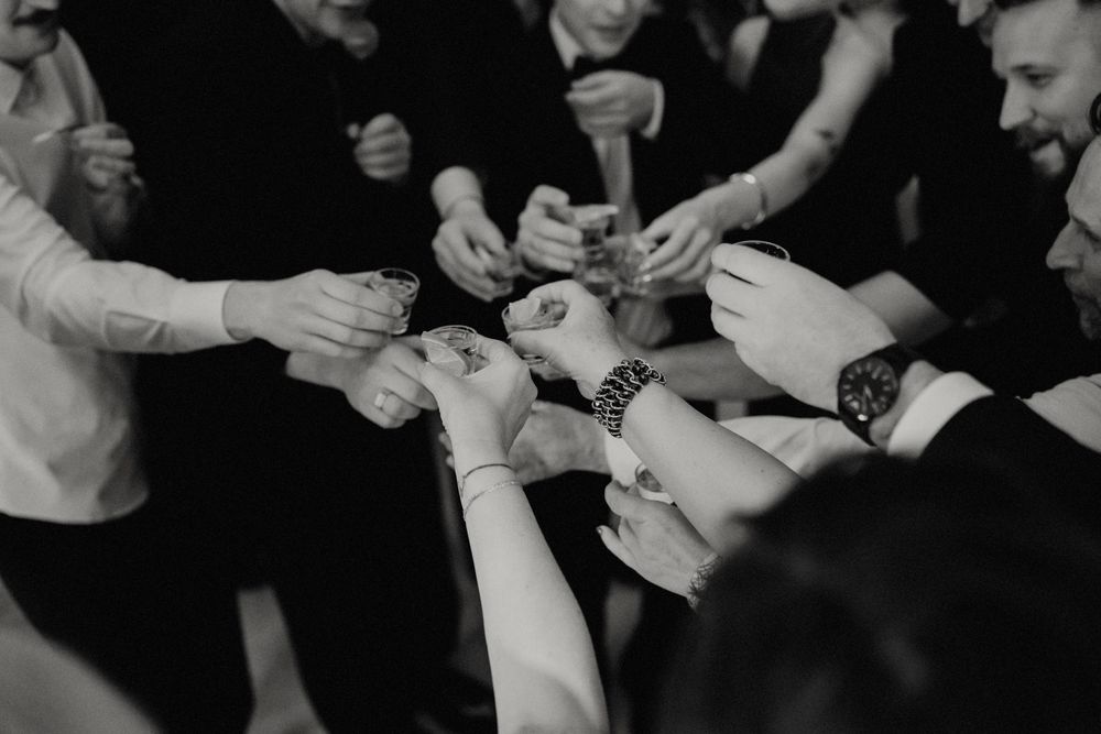Monochrome shot of hands holding drinks during a social celebration.