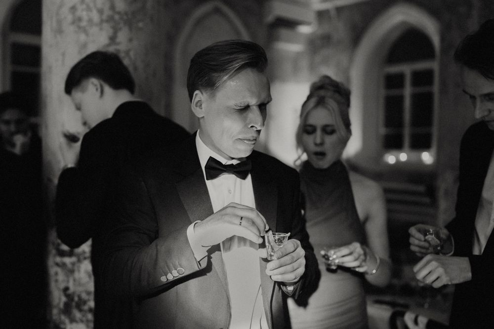 Elegant party guest in black bow tie enjoying drinks at formal evening event.