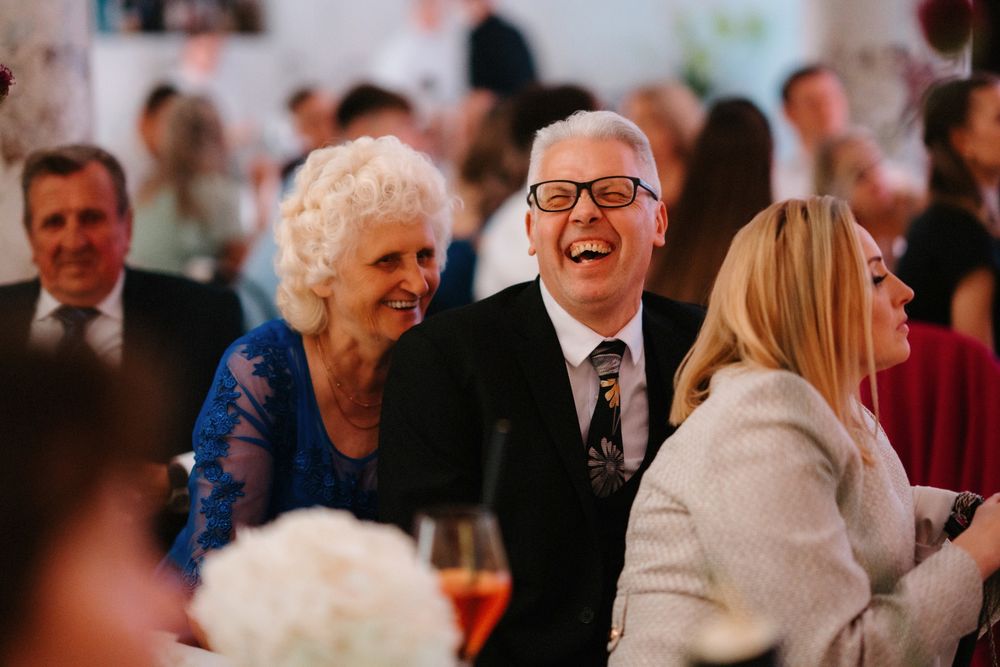Guests sharing joyful laughter during formal dinner celebration.