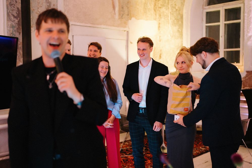 Party guests socializing and singing at indoor celebration event.
