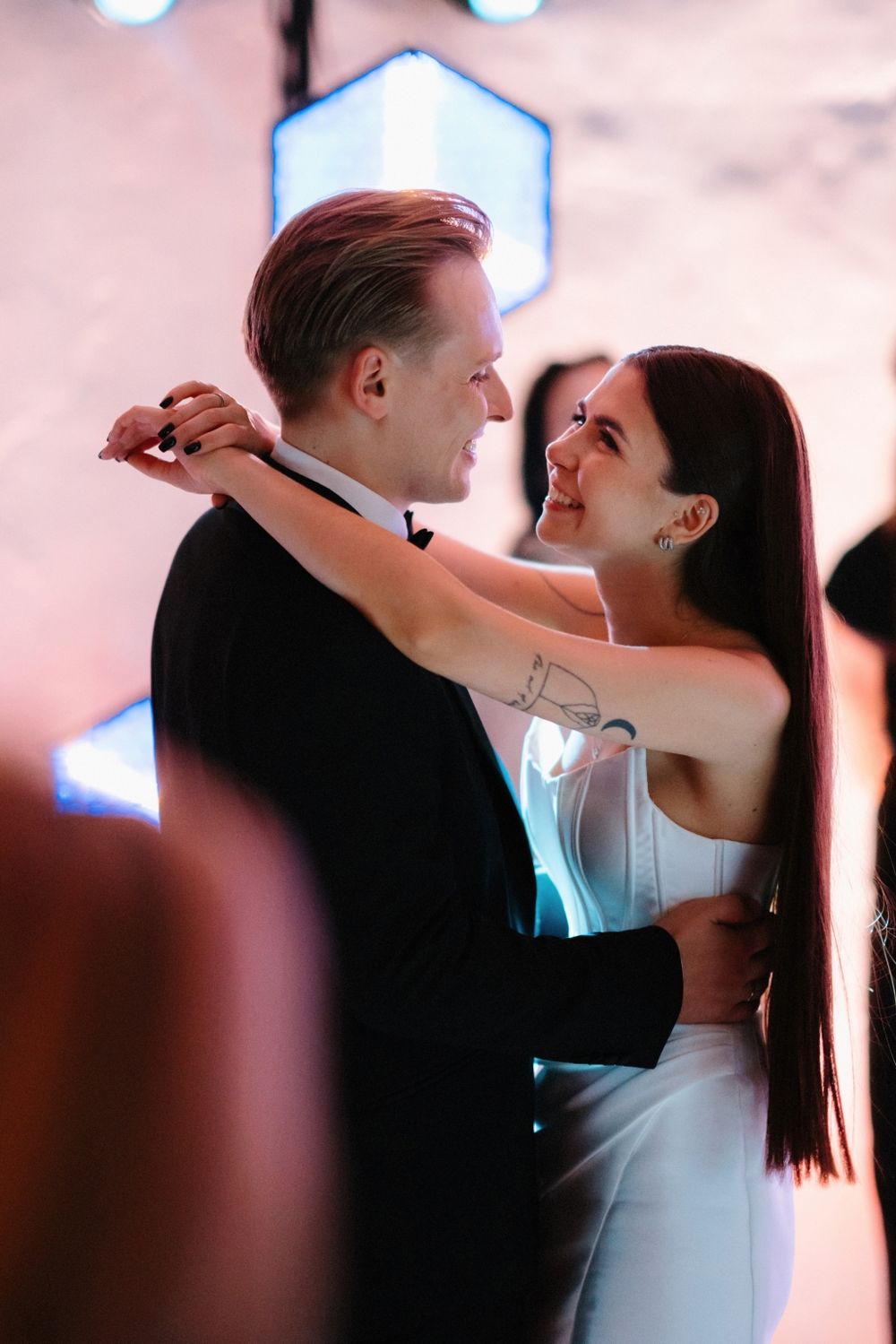 Couple sharing romantic first dance moment under blue hexagonal lighting.