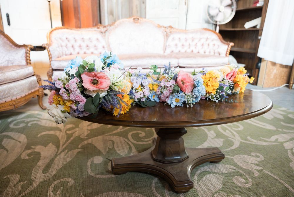 A decorative floral garland with colorful pastel flowers adorns the edge of a glass serving platter.