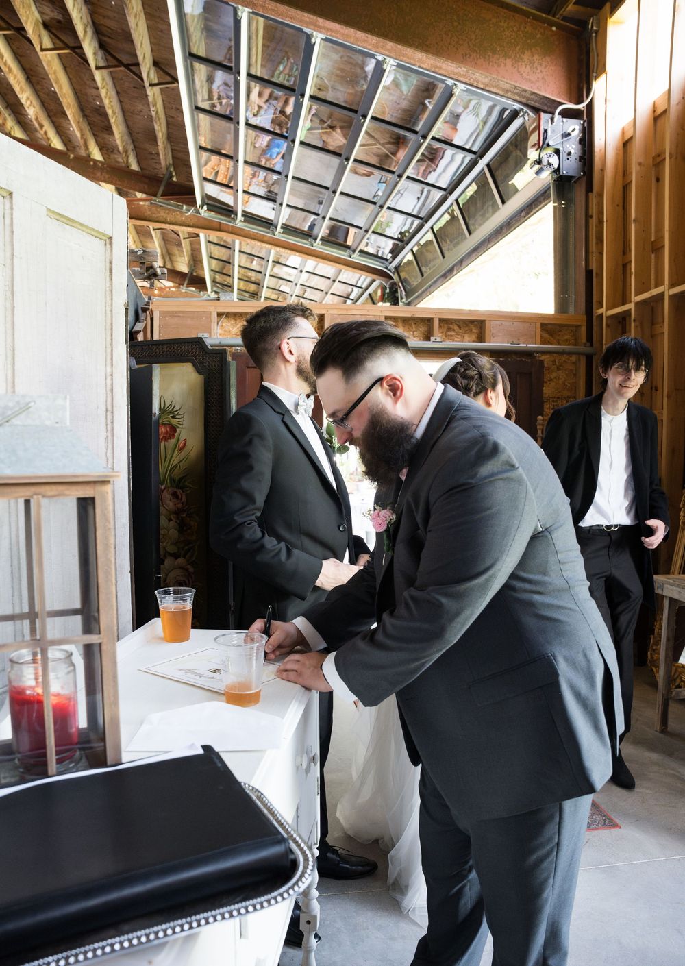 Multiple formal shots of groomsmen getting ready in a rustic venue with wooden walls and natural lighting.
