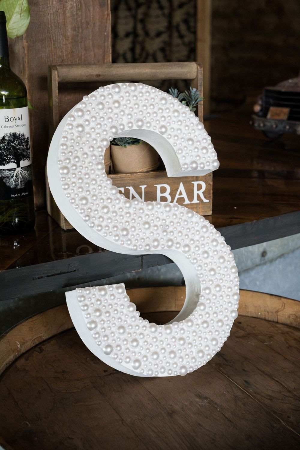 A collection of large, white decorative letter S signs with textured patterns displayed on a dark wooden surface.