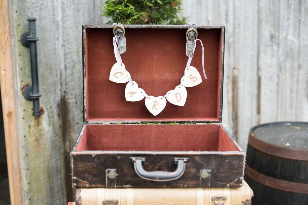 Vintage perfume bottles and jewelry displayed on rustic wooden boxes against a weathered backdrop.