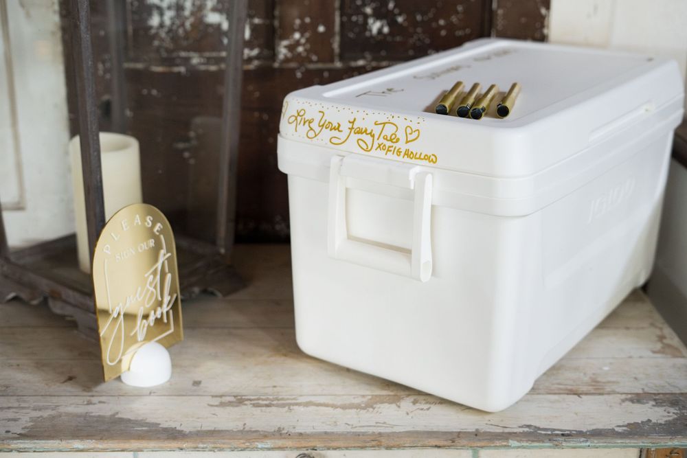 Three white paper boxes with gold lettering sit on a wooden surface in a vintage industrial setting.