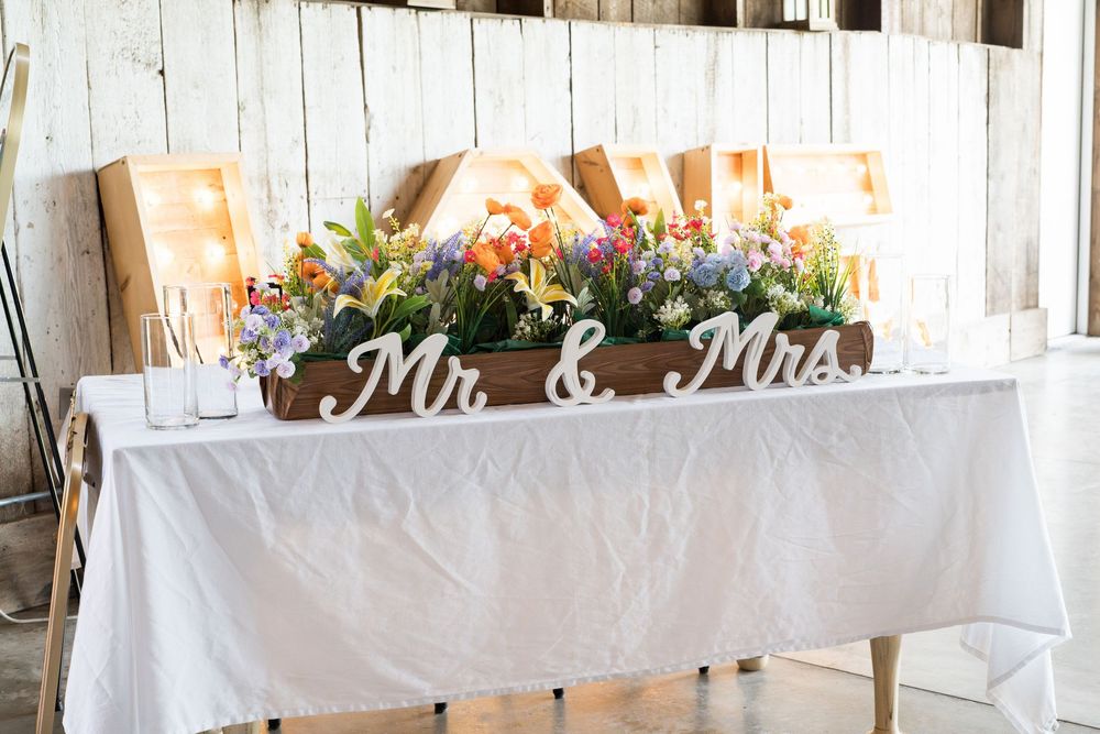 A rustic wedding reception venue with white tablecloths and wooden wall decorations.