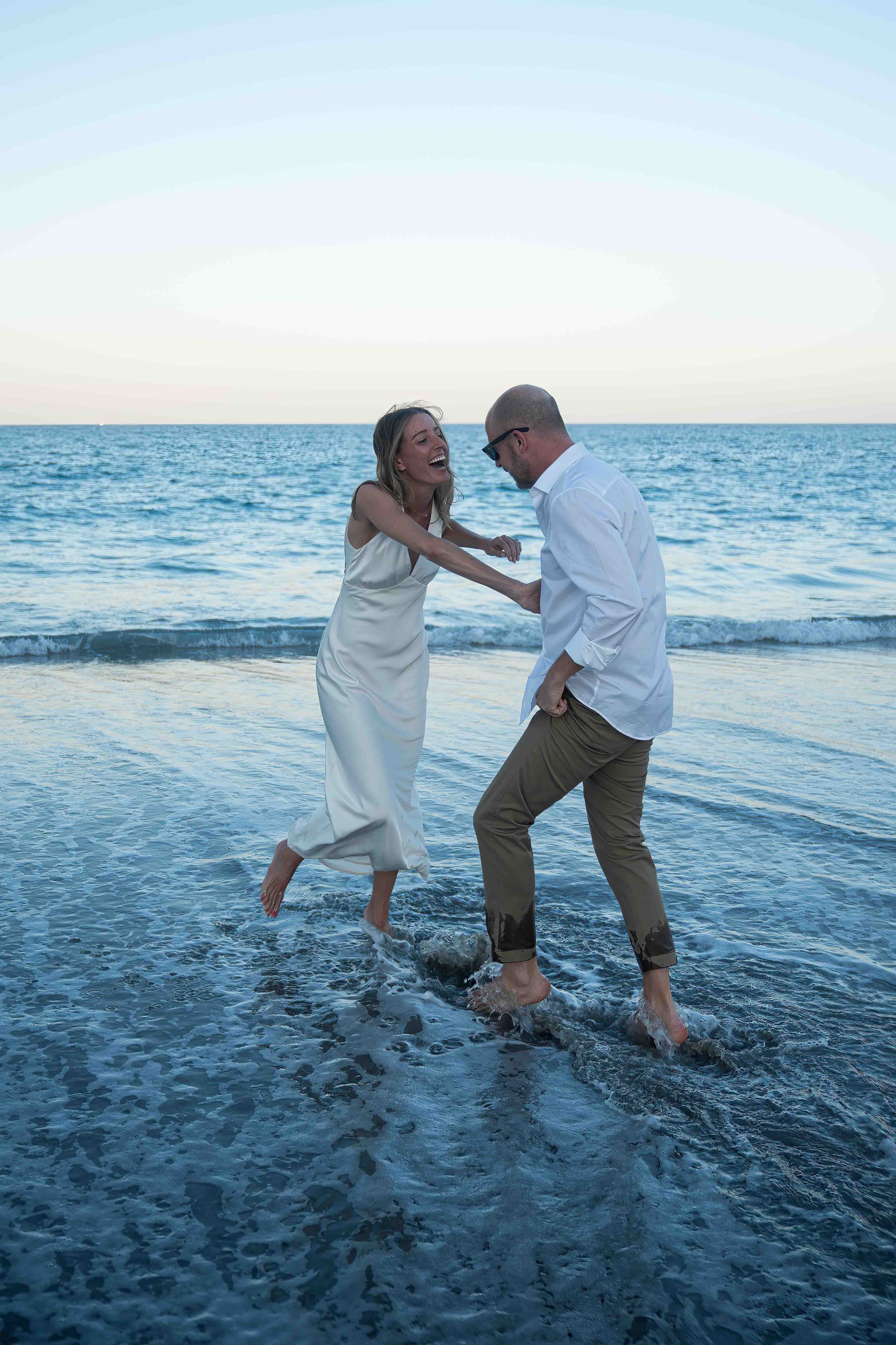 kari and jeff being playful on the beach at worth ave during an engagement photo shoot in palm beach, florida