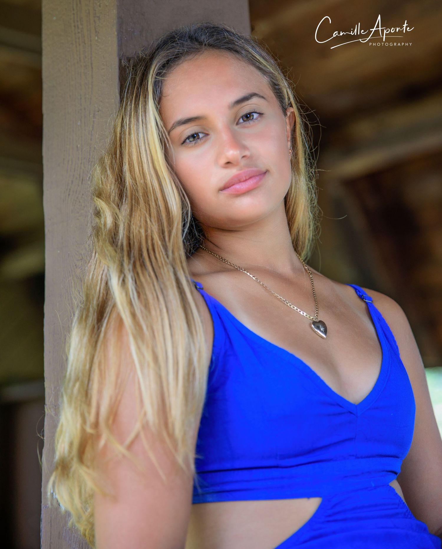 Portrait against a wooden pillar shows an athletic look in vibrant blue activewear.