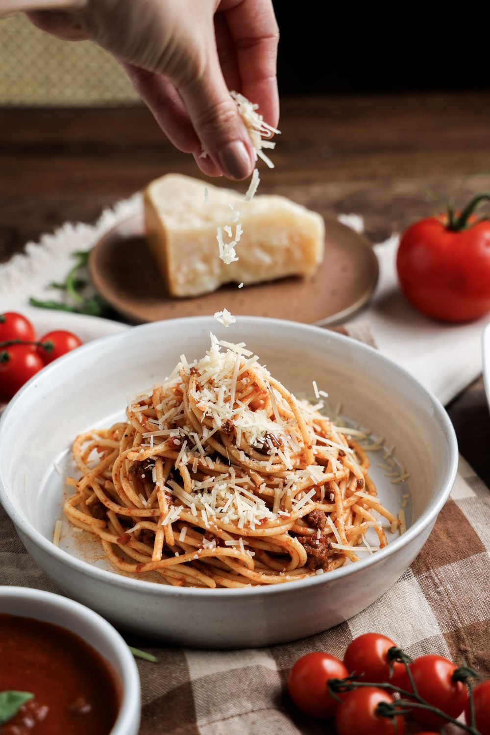 Spaghetti pasta dish with grated parmesan cheese and cherry tomatoes.