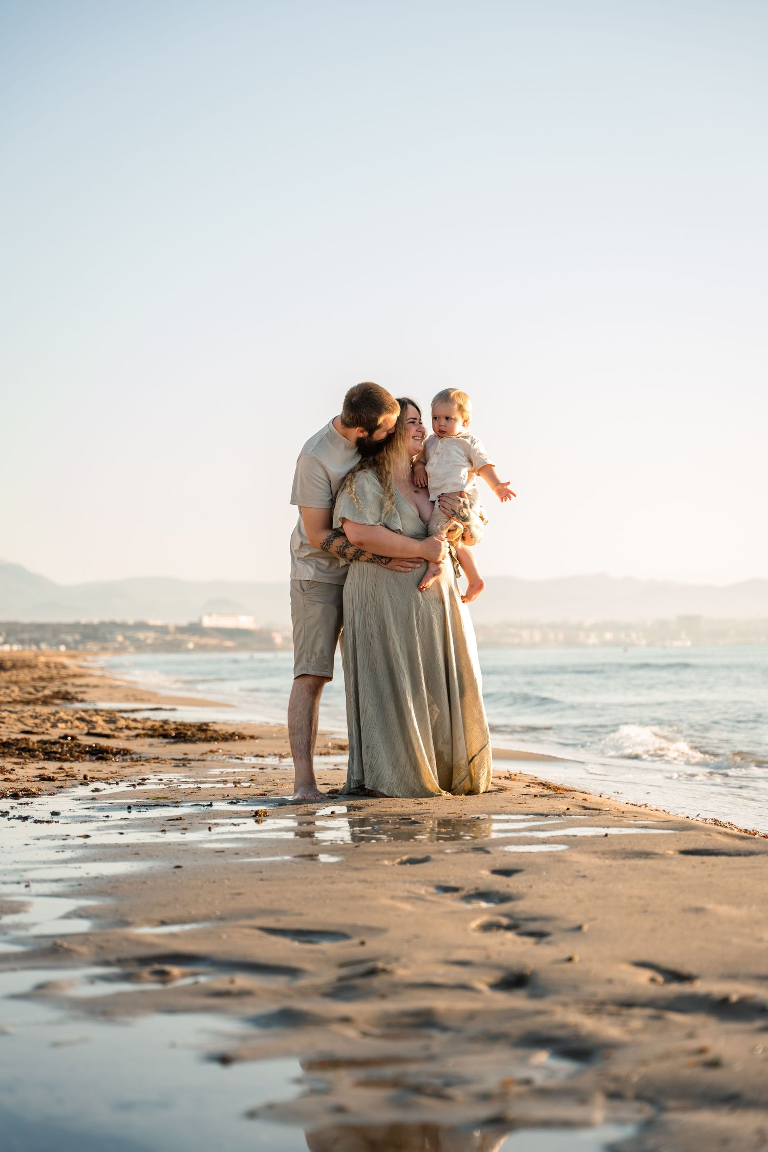 family of 3 with young boy on the beach with soft golden light and sand with water reflections in Alicante Spain