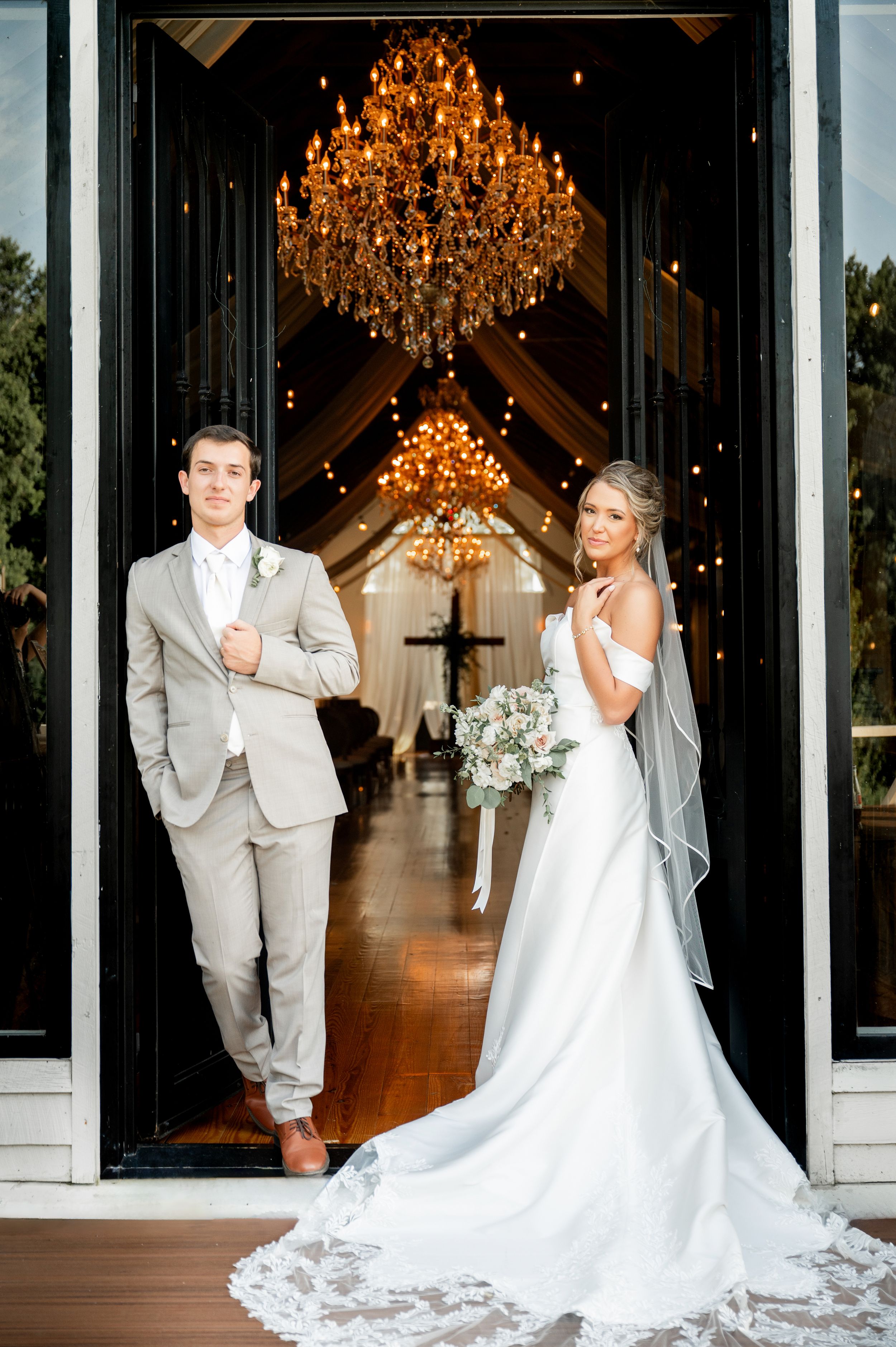 Elegant wedding venue interior with chandeliers and white draping.