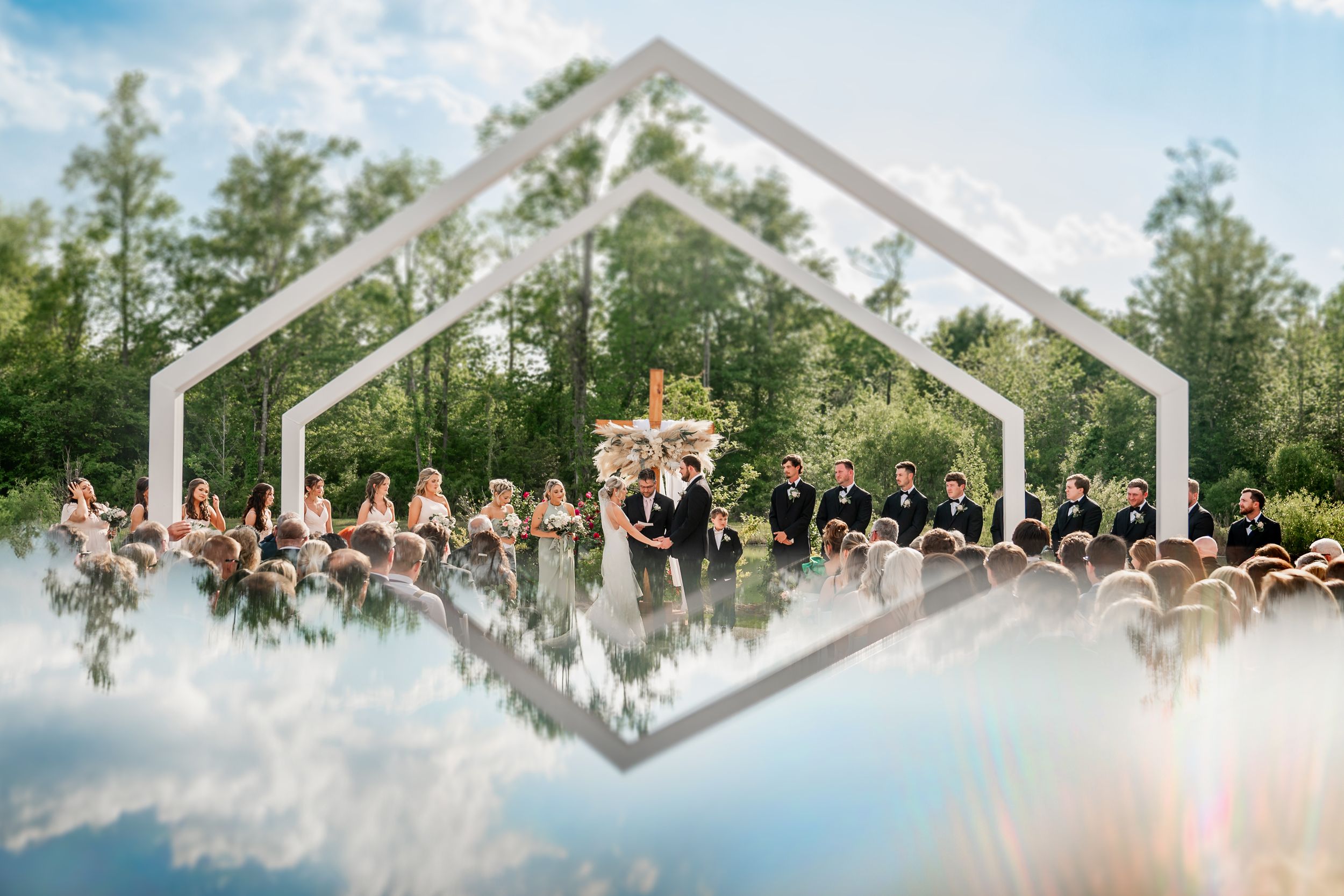 Panoramic view of a wedding ceremony setup with white chairs and floral arrangements outdoors.