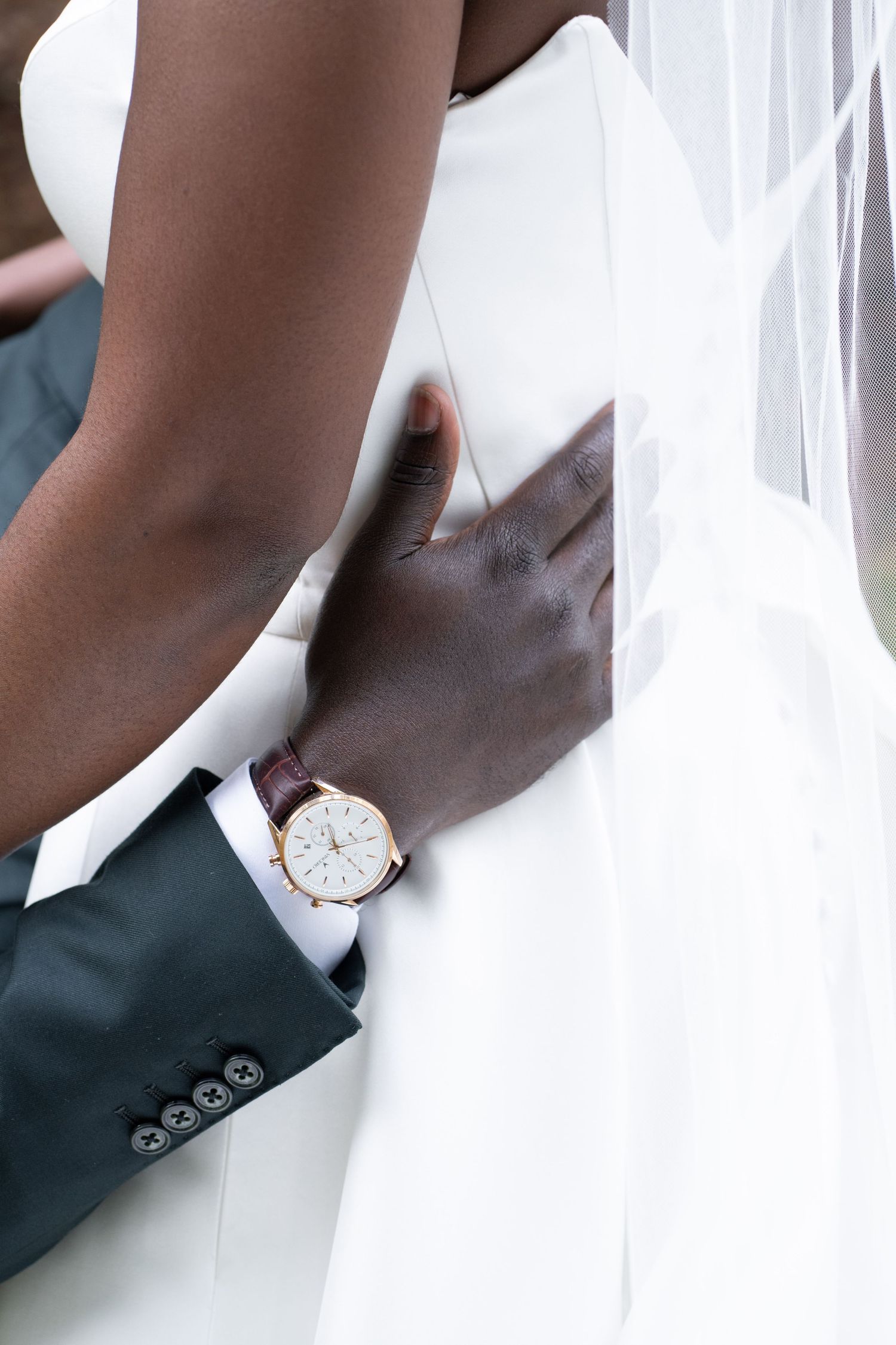 Groom places his hand on bride's waist, showcasing an elegant rose gold watch on their wedding day.