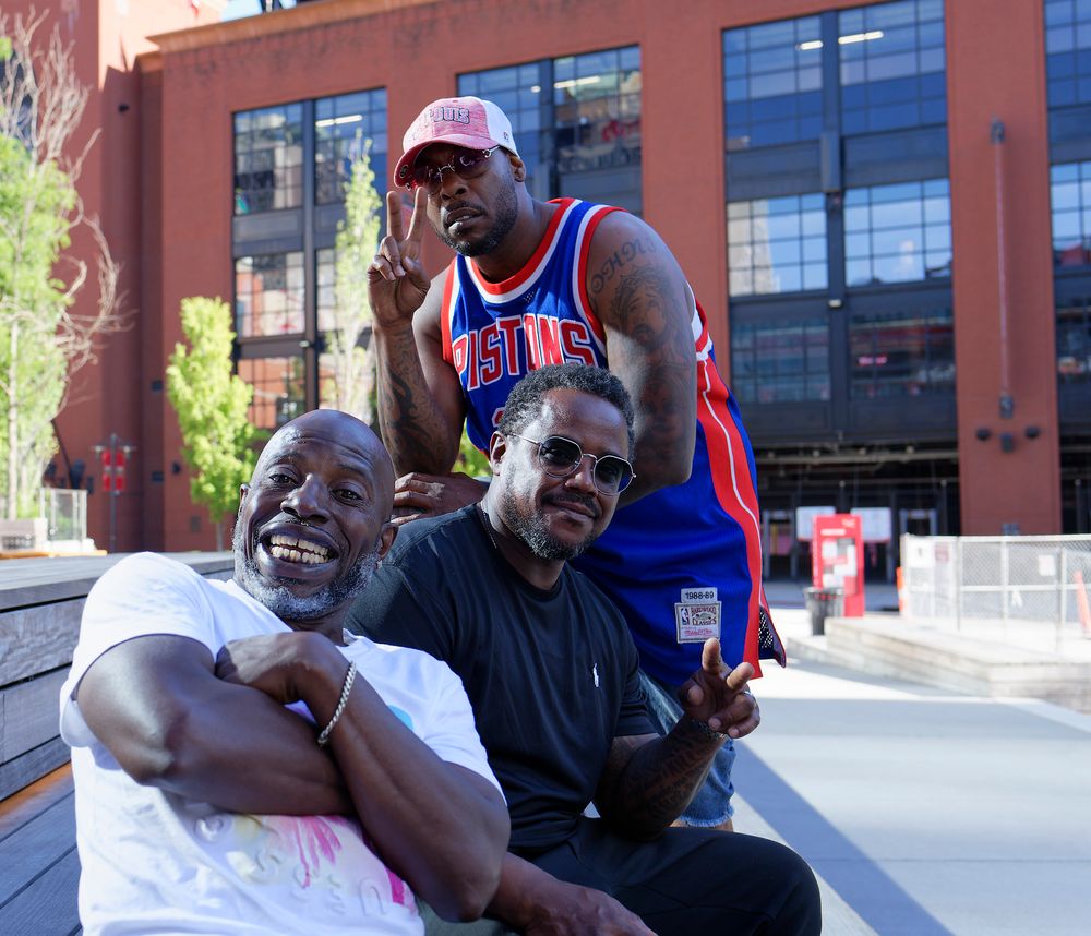 Three friends sharing laughs while sitting outdoors in urban setting.