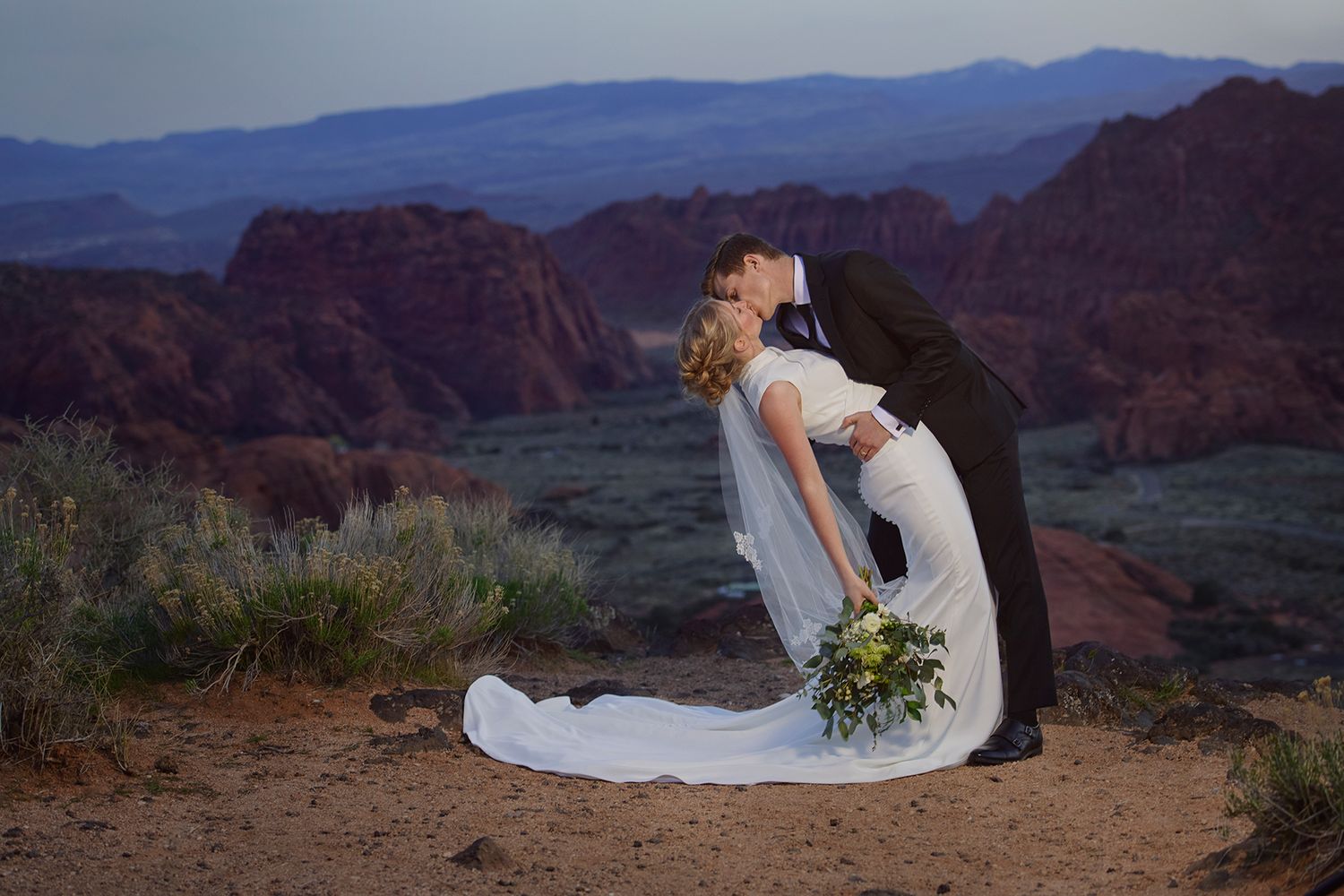 Blackfoot Wedding Photographer A romantic wedding scene at sunset with mountain backdrop in Snow Canyon State Park, Utah.