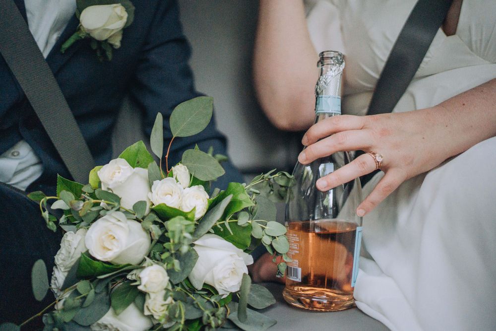 Candid shot of a couple riding in the back of a car after their elopement, holding a bottle of wine  | Shannon Konek, Pittsburgh Photographe