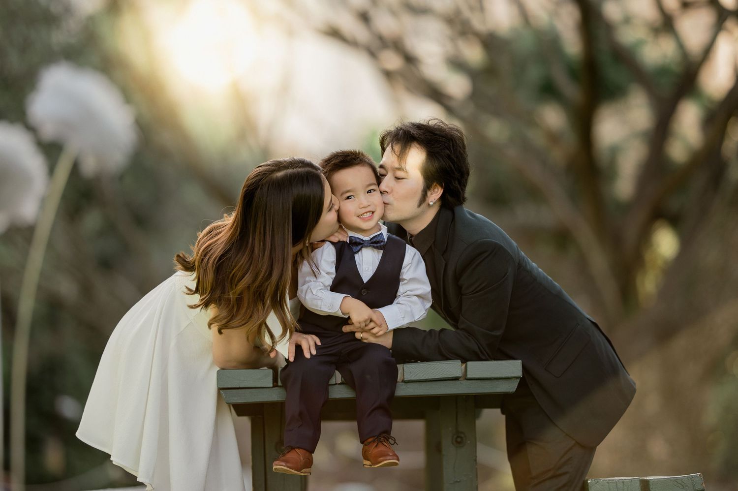 Family sharing tender moment together on park bench at sunset.