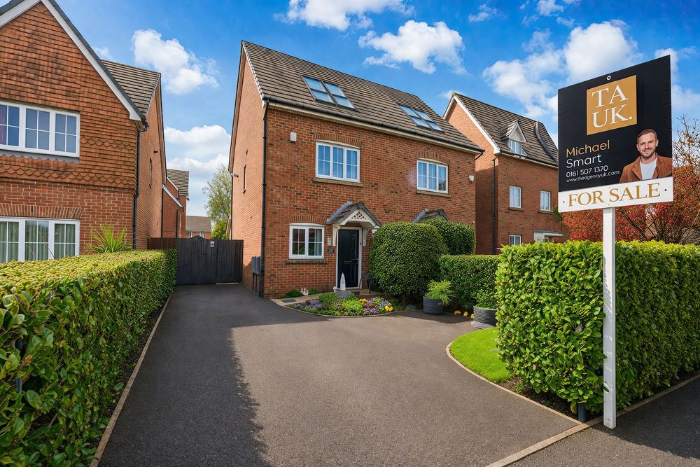 A red brick detached house for sale with a tarmac driveway, manicured hedges, and a For Sale sign on a sunny day.