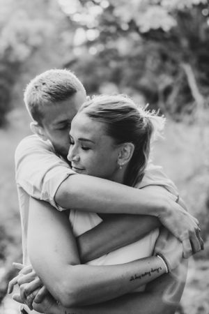 Black and white intimate portrait of couple embracing in tender moment outdoors.