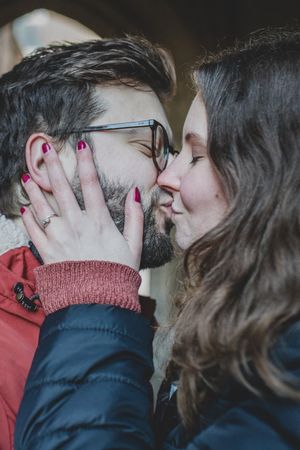 Romantic close-up of couple sharing intimate moment with red nail polish visible on hands.