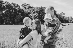 Black and white family portrait of parents with children in open field.