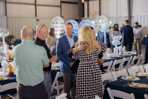 Attendees seated at round tables during a formal dinner event with white tablecloths and decorative centerpieces.