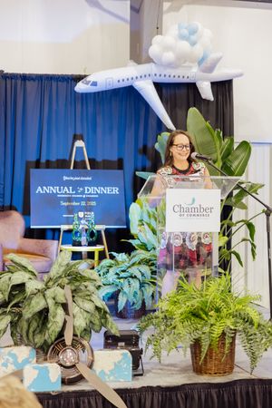 Chamber event display with potted plants and blue curtain backdrop featuring signage for annual dinner.