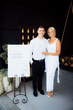 Wedding rehearsal photo session with couple holding white signs against dark background.