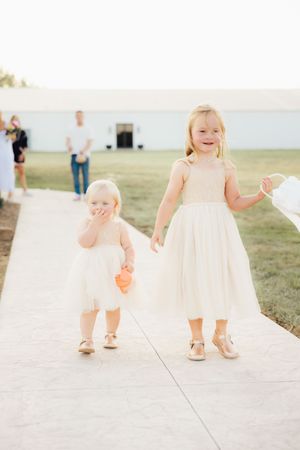 Close-up view of flower girls walking on concrete pathway.
