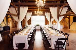 Elegant barn venue with crystal chandeliers and white draping.