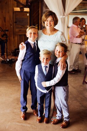 Family group poses together at rustic barn venue wearing formal attire.
