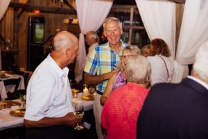 Guests enjoying refreshments and conversation at rustic barn reception.
