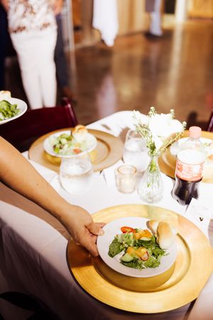 Branding and event session with hand serving elegant plated salad with gold charger at formal dinner event.