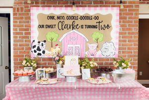 Pink and white party banner with farm animals and text decorations on brick wall.