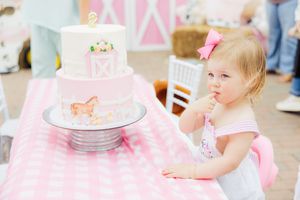 Pink gingham tablecloth with white cake and party decorations.