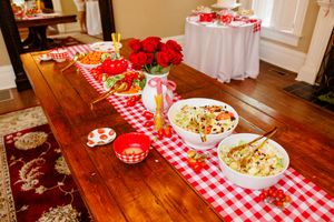 A rustic wedding reception table decorated with red and white checkered tablecloths and floral centerpieces.
