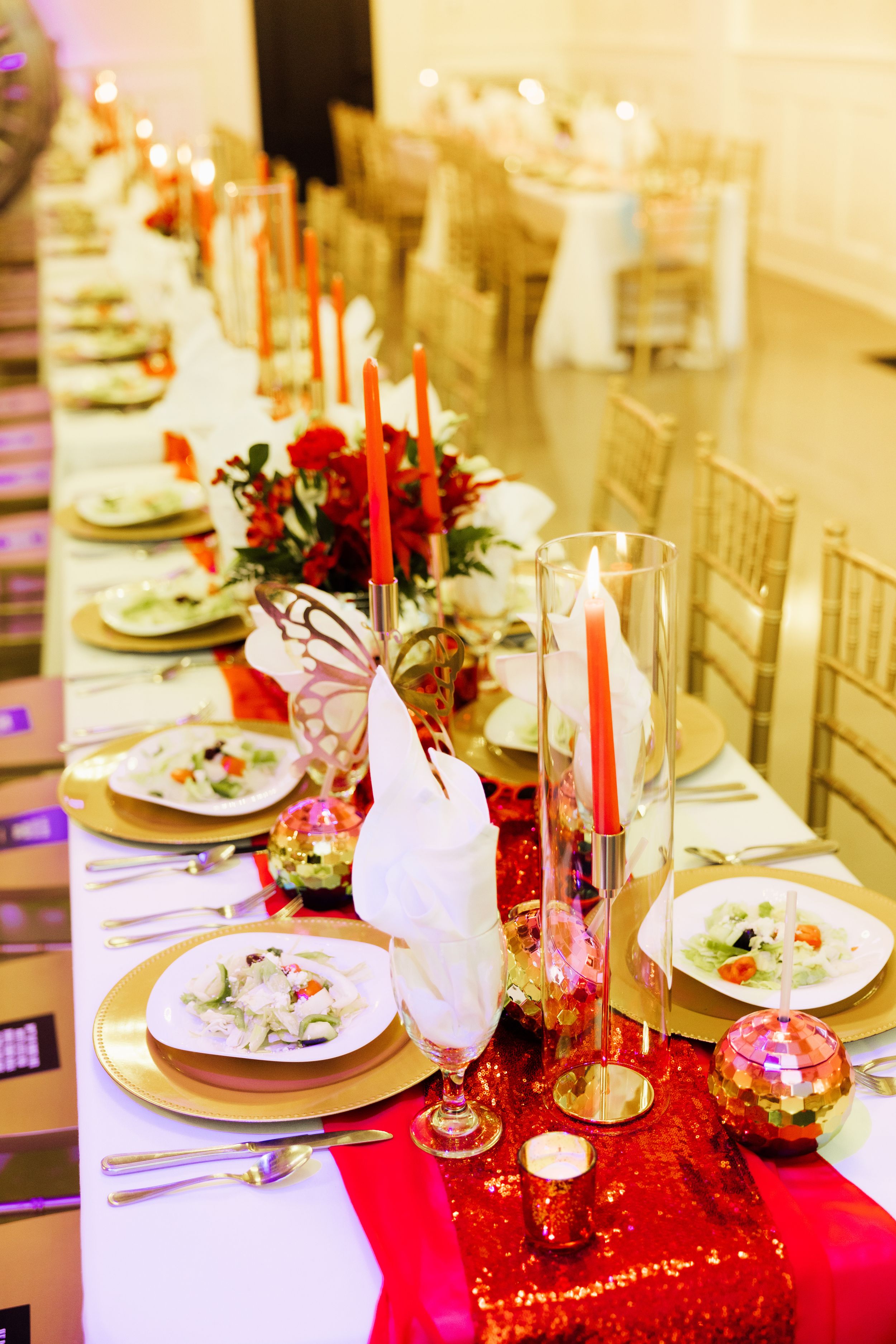 Branding and event session with elegant table setting with red and gold decor, candles, and place settings.